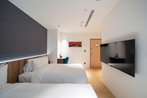 A modern hotel room with two beds, a flat-screen TV mounted on the wall, and a wooden door in the background. - Kashotsu Bettei (Taichung)