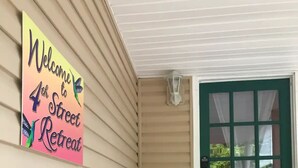 A porch with a 'Welcome to 4th Street Retreat' sign, a green door, and a small staircase leading up. - Spacious 3 Bedroom in Downtown Danville: Welcome to 4th Street Retreat (Danville)