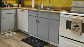 A kitchen with grey cabinets, a white stove, and a yellow wall. - Spacious 3 Bedroom in Downtown Danville: Welcome to 4th Street Retreat (Danville)