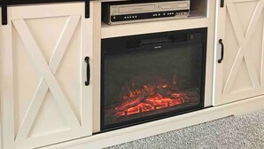 A flat-screen TV mounted on a wooden cabinet with a built-in fireplace below. - Spacious 3 Bedroom in Downtown Danville: Welcome to 4th Street Retreat (Danville)