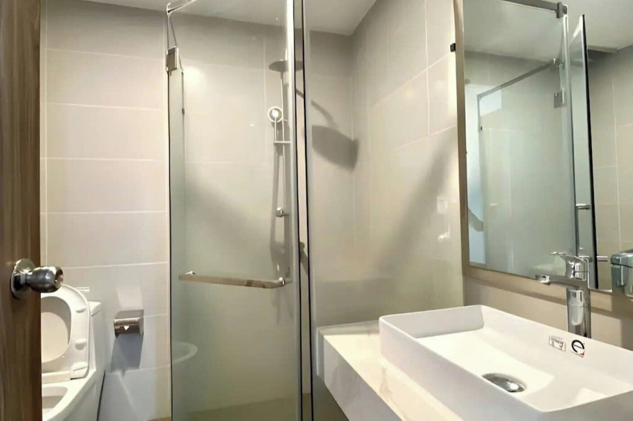 A modern bathroom with a glass shower enclosure, a white sink, and a toilet.