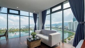 Ein modernes Hotelzimmer mit großem Fenster, einer Couch, einem Couchtisch und einem Sessel.