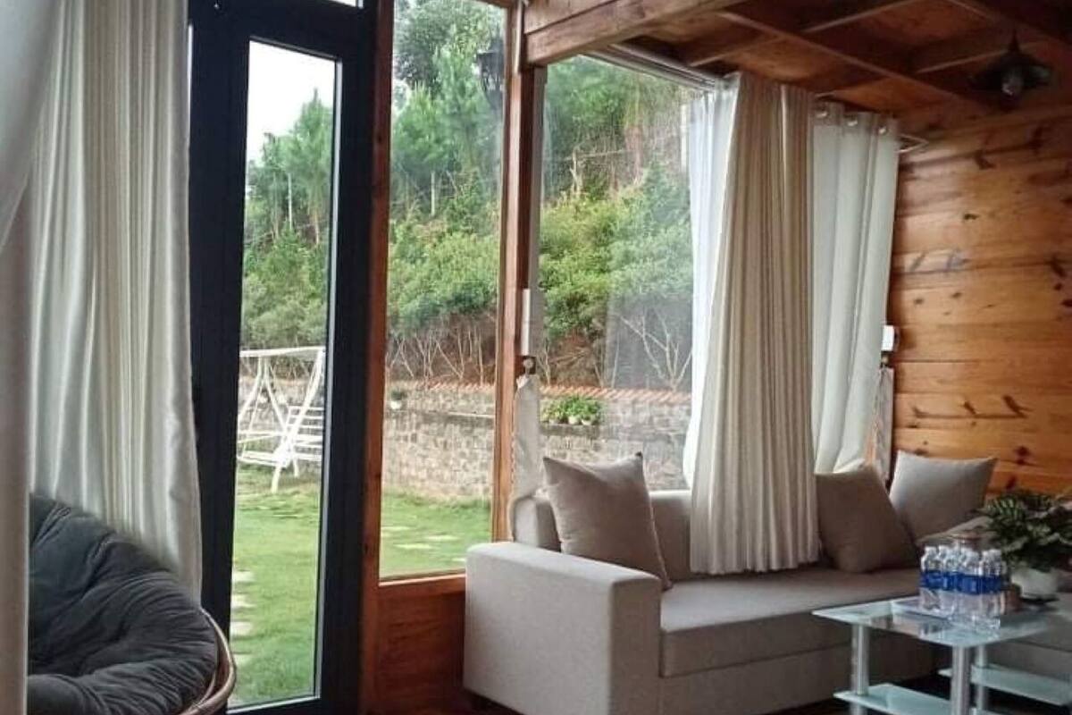 Ein gemütliches Blockhauss-Interieur mit Holzbalkendecke, einer Couch, einem Sessel und einem Glastisch.
