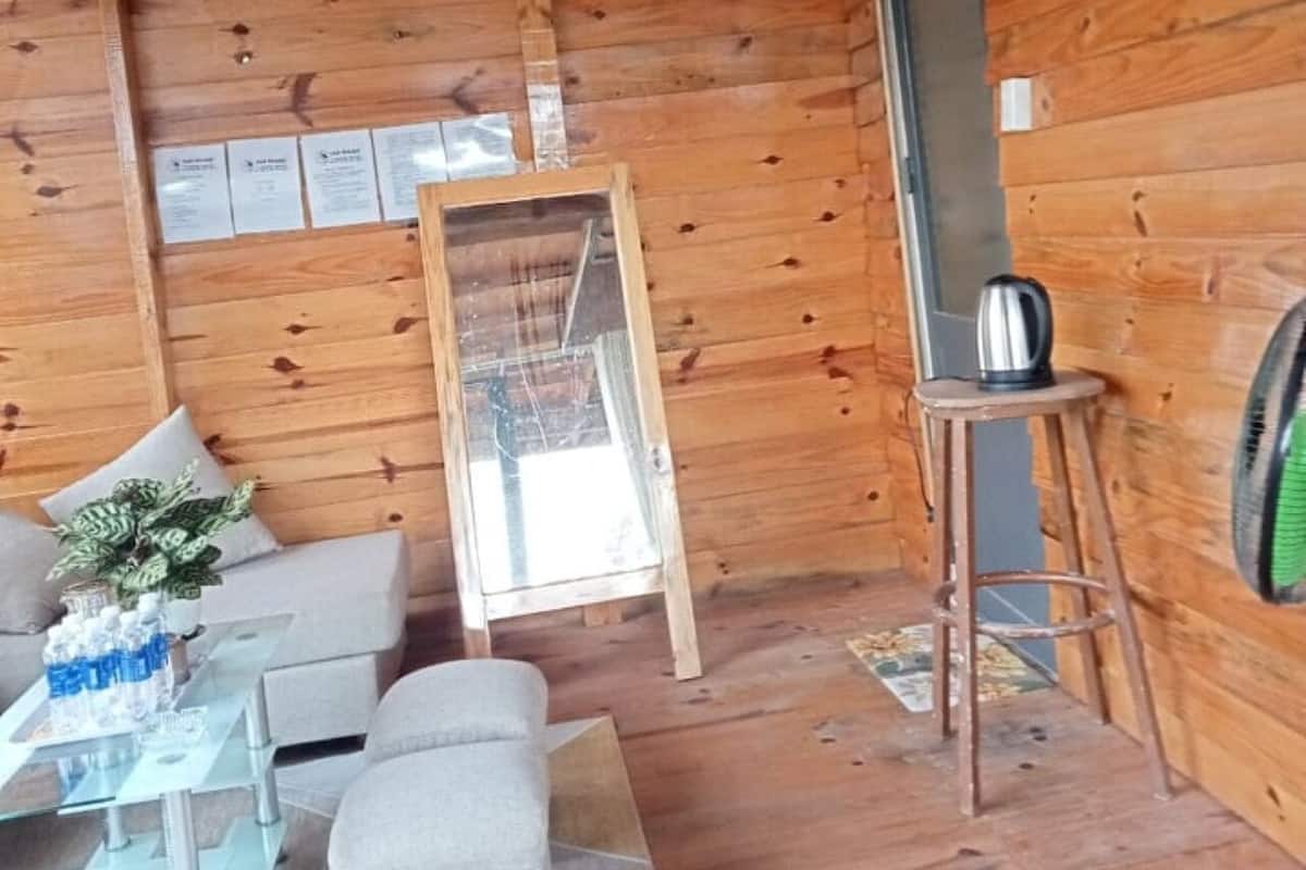 Ein Holzblockhaus-Innenraum mit einer Couch, einem kleinen Tisch mit einer Vase und einem an der Wand angelehnten Spiegel.