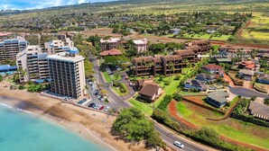 An aerial view of a coastal resort area with beachfront properties, a large hotel, and a golf course.
