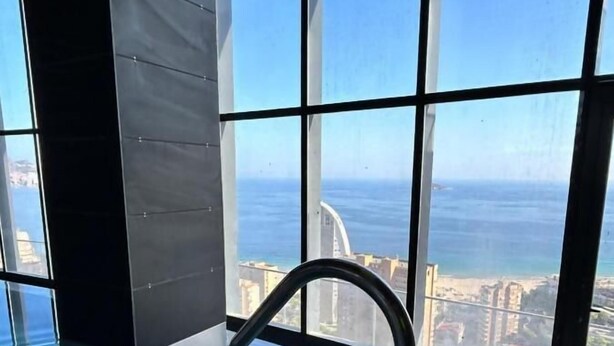 An indoor swimming pool with a clear view of the ocean and cityscape through large windows. - Benidorm Beach Belluba Luxury bay (Benidorm)