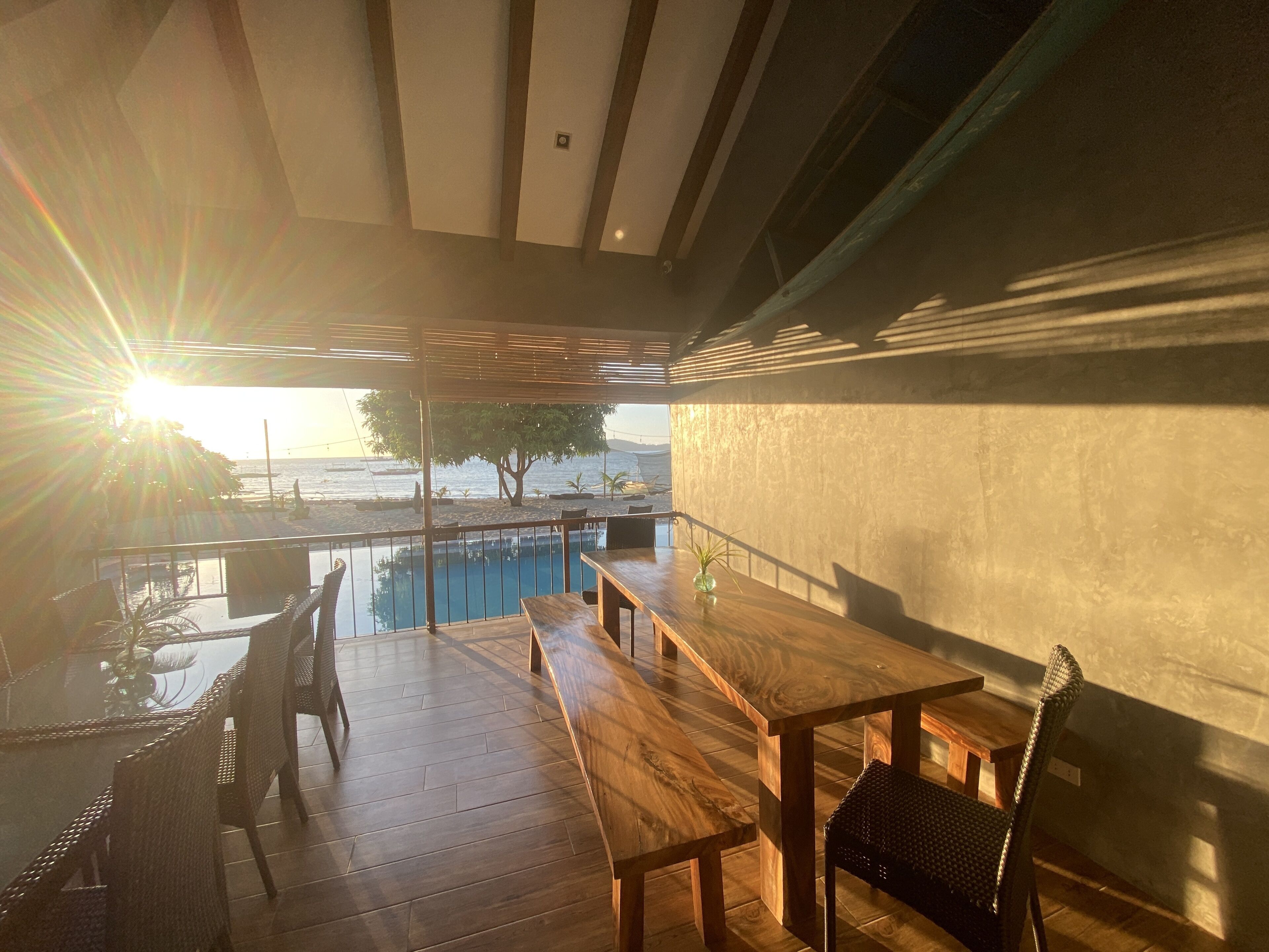 A wooden deck with a pool, outdoor seating, and a view of the sea.