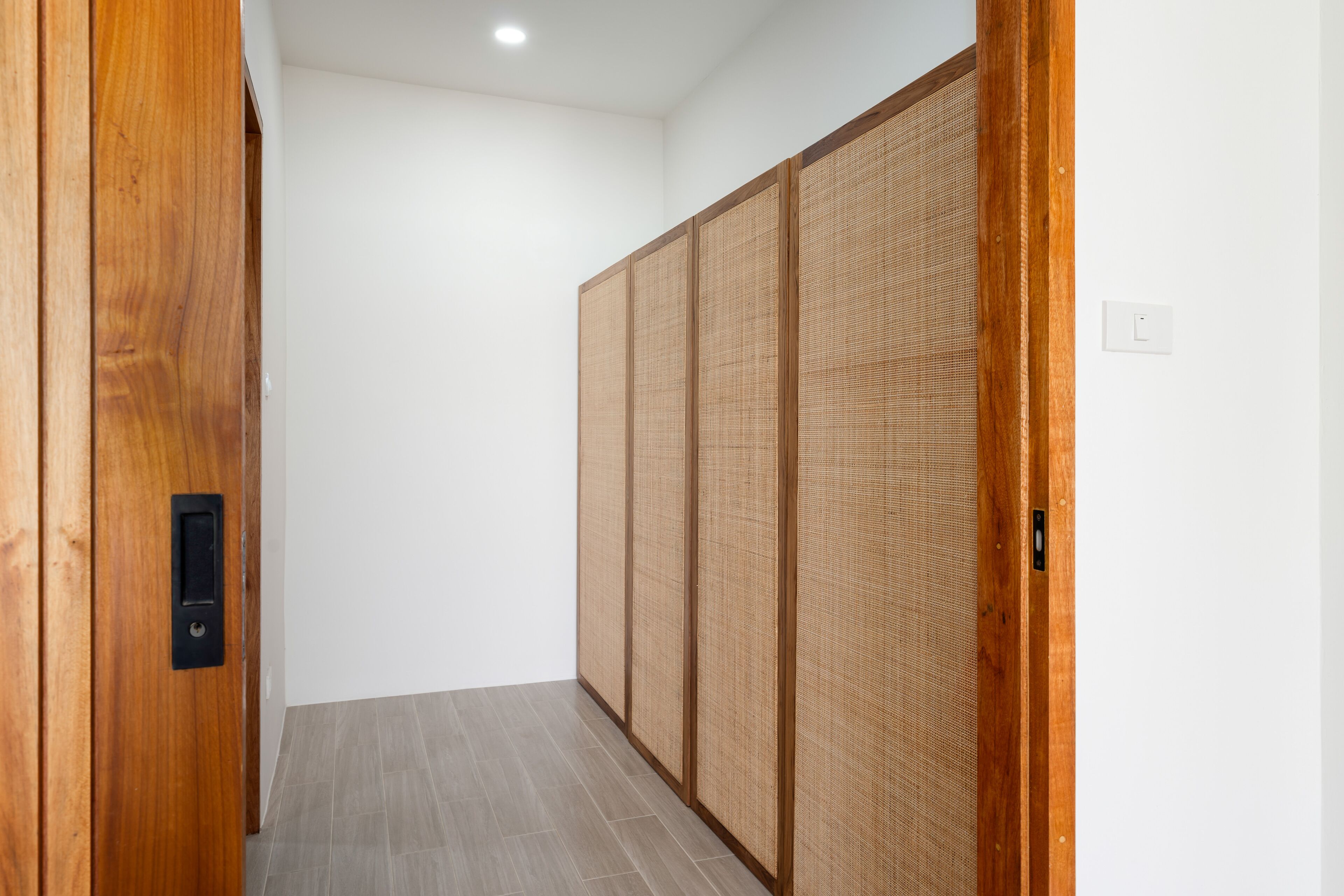 A hallway with a wooden door, a sliding shoji screen, and a light switch on the wall.