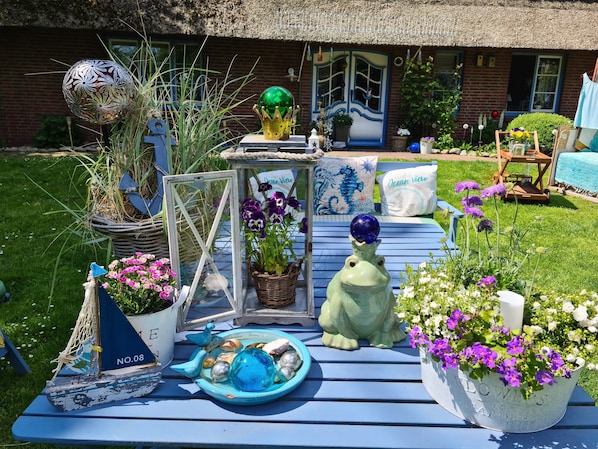 A garden table with various decorative items, including a blue bird sculpture, a green frog sculpture, and a blue bowl with decorative items.