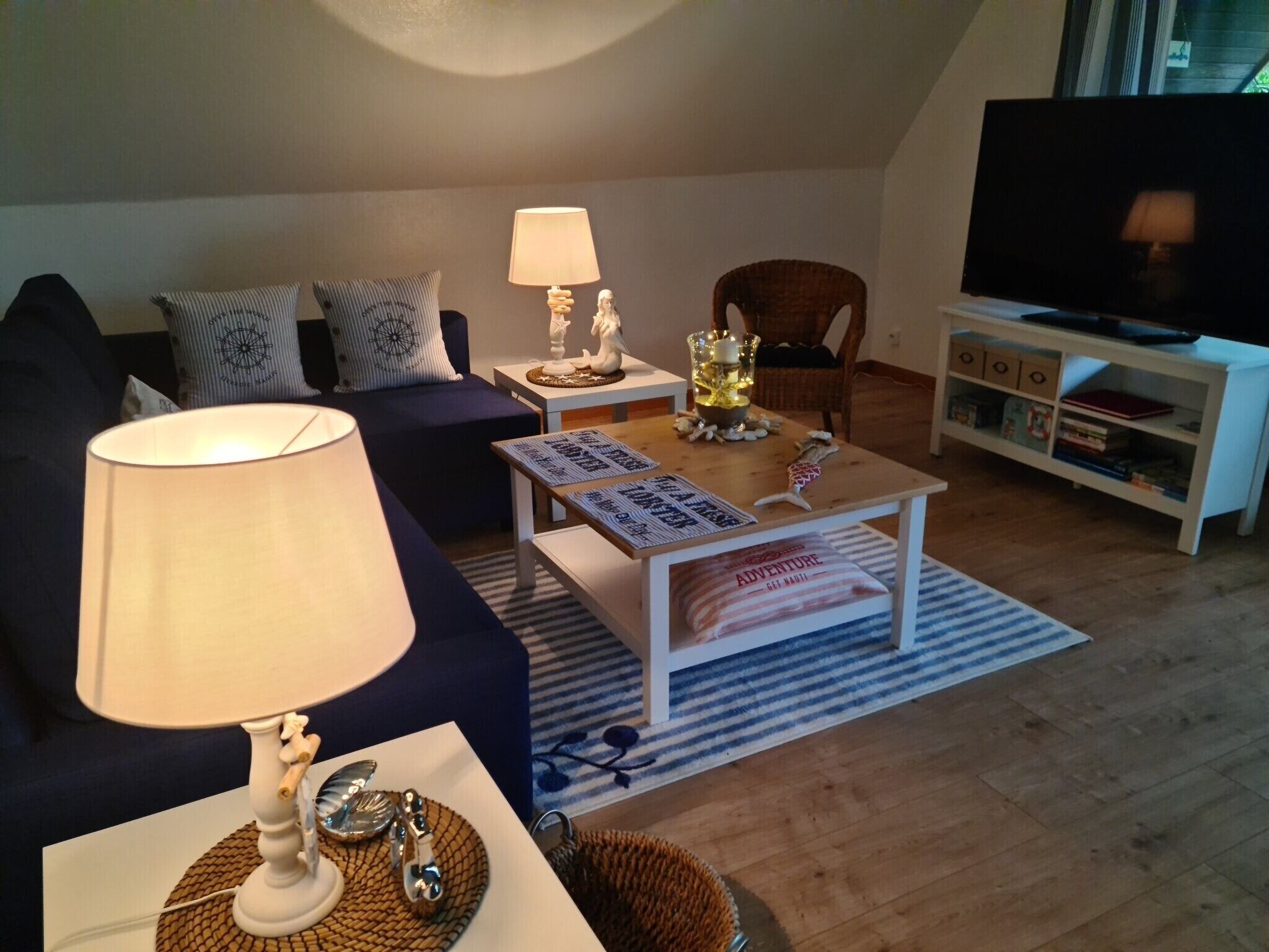 A living room with a sofa, a coffee table, a lamp, a TV, and a bookshelf.