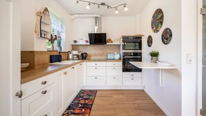 Une cuisine moderne avec des meubles blancs, un plan de travail en bois, un four encastré et un four à micro-ondes.