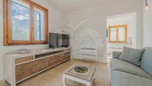 Una sala de estar moderna con televisor, una mesita y un sofá.