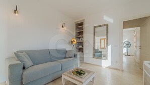 Una sala de estar moderna con un sofá gris, una mesa de centro de vidrio y una estantería.
