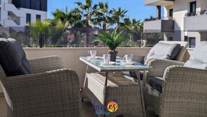 Un espace extérieur aménagé avec des meubles en osier, une petite table et une plante en pot.