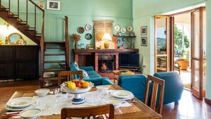 Zona pranzo con tavolo apparecchiato per quattro persone, camino e scala che conduce a un altro piano.