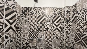 A shower area with a black and white patterned tile wall. - Apartment 32mt2 Tultitlán Edomex. Near the municipal palace. Beautiful garden  (Tultitlán de Mariano Escobedo)