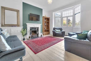 A living room with a fireplace, two sofas, a red rug, and a large window. - Simply Hove By My Getaways (Hove)