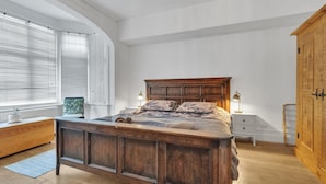 Un dormitorio con una cama de madera grande, paredes blancas y un armario de madera.