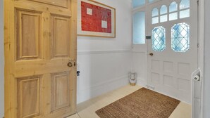 Una puerta de madera, una pared blanca con una obra enmarcada, y una puerta blanca con vidrieras.