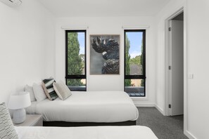 A bedroom with a bed, two windows, and a door.