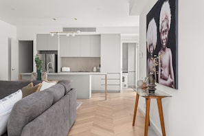 A modern kitchen with white cabinets, a central island, and a dining area with a glass table.