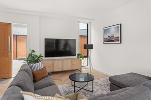 A modern living room with a flat-screen TV, grey sofas, a coffee table, and a framed picture on the wall.
