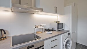 A modern kitchen with white cabinets, a built-in microwave, a stove, and a washing machine. - Athina in Chalandri With 2 Bedrooms and 1 Bathrooms (Chalandri)