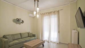 Ein Wohnzimmer mit einem grünen Sofa, einem Holztisch, einer Pendelleuchte und einer Heizung.