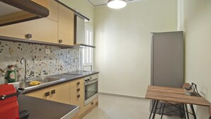 Eine kompakte Küche mit Arbeitsplatte, Spüle, Backofen und einem kleinen Esstisch mit Stühlen.
