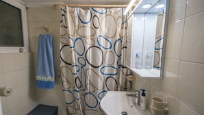 A bathroom with a shower curtain, a sink, a mirror, and a towel rack. - Marina Apartment in Nikea (Nikaia-Agios Ioannis Rentis)