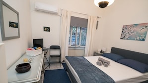 A bedroom with a bed, a desk, a chair, a window with curtains, and a painting on the wall. - Marina Apartment in Nikea (Nikaia-Agios Ioannis Rentis)