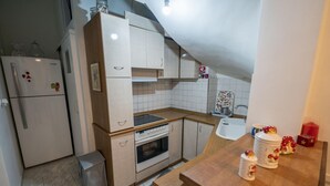 A compact kitchen with a refrigerator, oven, and sink. - Marina Apartment in Nikea (Nikaia-Agios Ioannis Rentis)