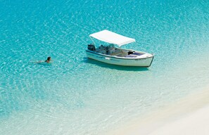 A boat with a canopy on a clear blue sea near a sandy beach. - The Artist s House in Paxi (Paxos)