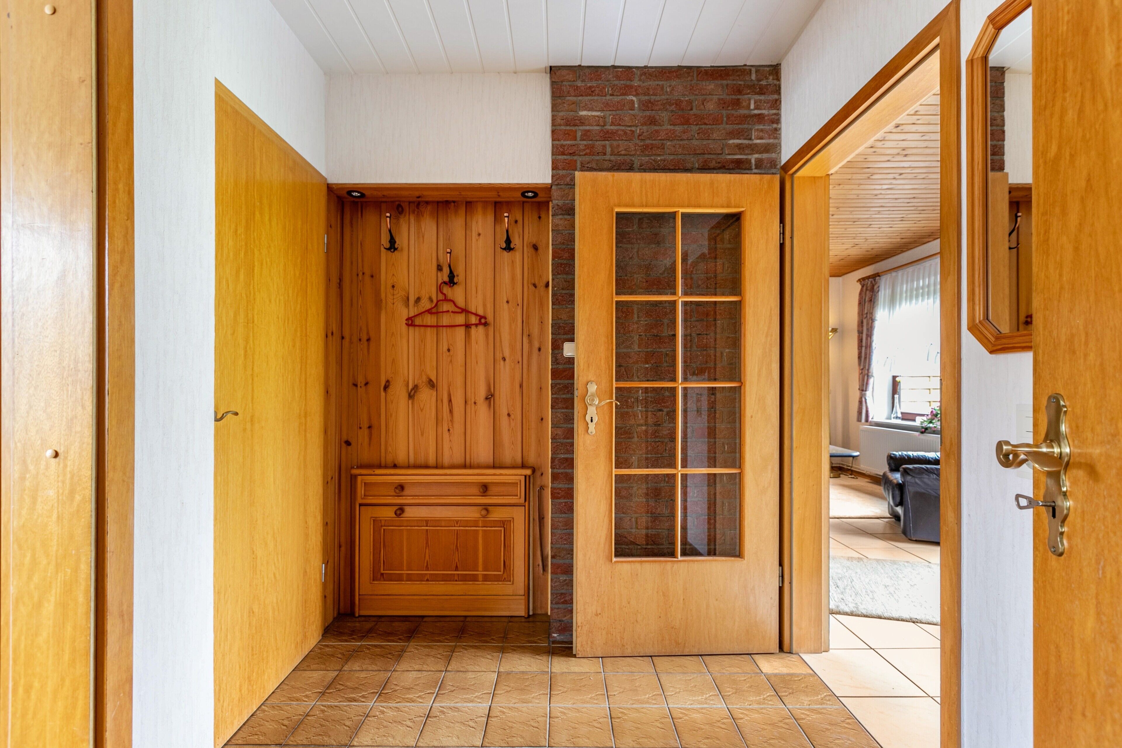 A hallway with a wooden door, a coat rack, and a bench.