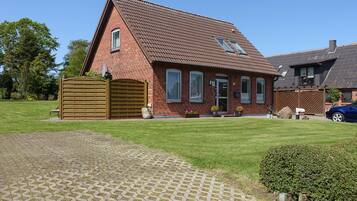 A brick house with a sloped roof, a wooden gate, and a paved driveway.