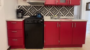 A compact kitchen with red cabinets, a black stove, and a coffee maker. - Apartamento 32mt2 Tultitlán Edomex. Cerca del Palacio Municipal. 3 Camas (Tultitlán de Mariano Escobedo)