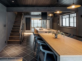 Una cocina moderna con escalera de madera, una barra larga y taburetes.