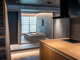 Un baño moderno con un ventanal grande, un tocador de madera y ducha integrada.