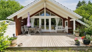 Eine Holzterrasse mit überdachter Sitzecke, einem Tisch und Stühlen.