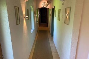 A hallway with framed pictures on the walls, a carpeted floor, and a door at the end. - Haus Breitenberg (Bad Hindelang)