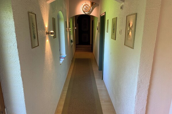 A hallway with framed pictures on the walls, a carpeted floor, and a door at the end. - Haus Breitenberg (Bad Hindelang)