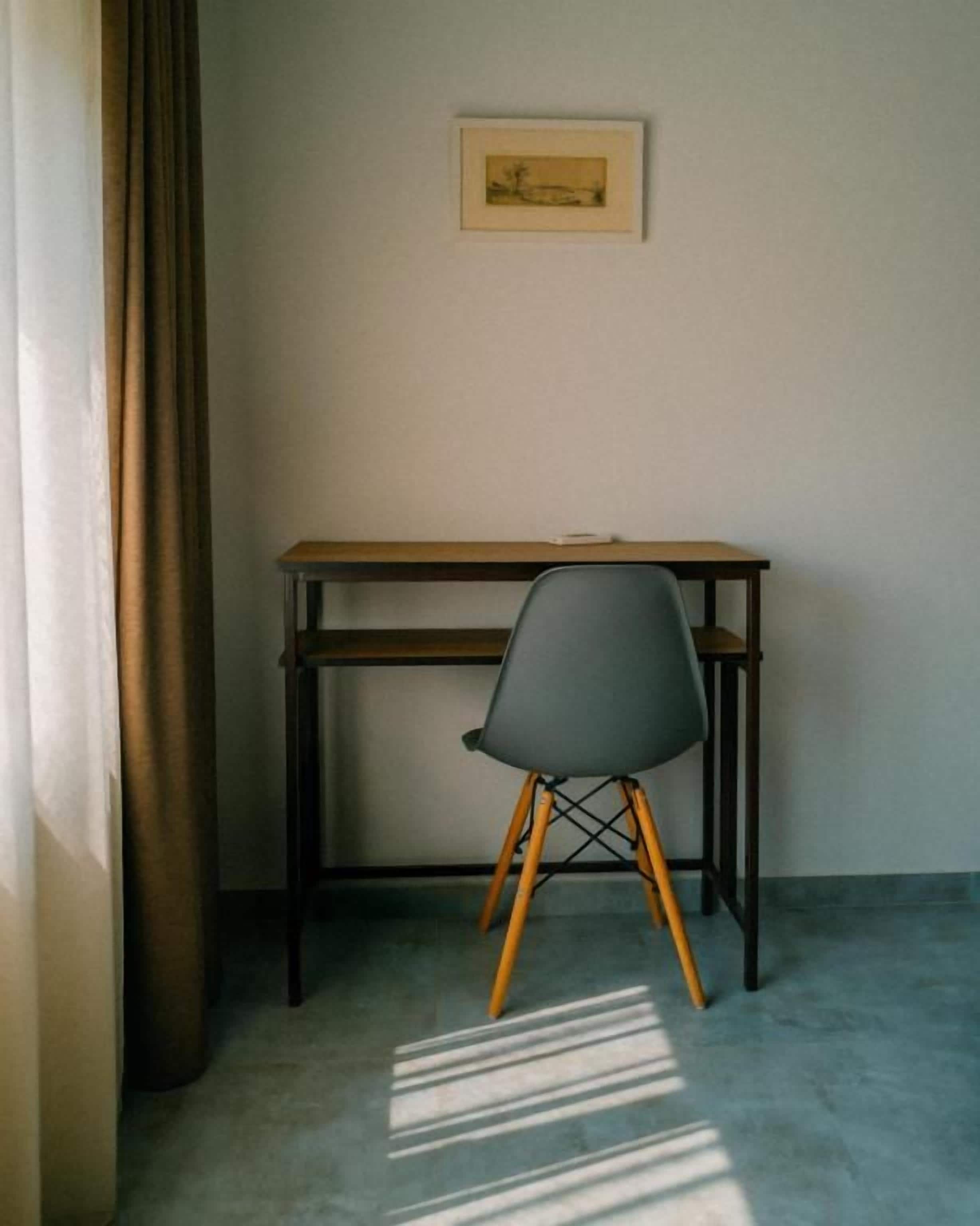 Una stanza con una scrivania, una sedia e un quadro appeso al muro.