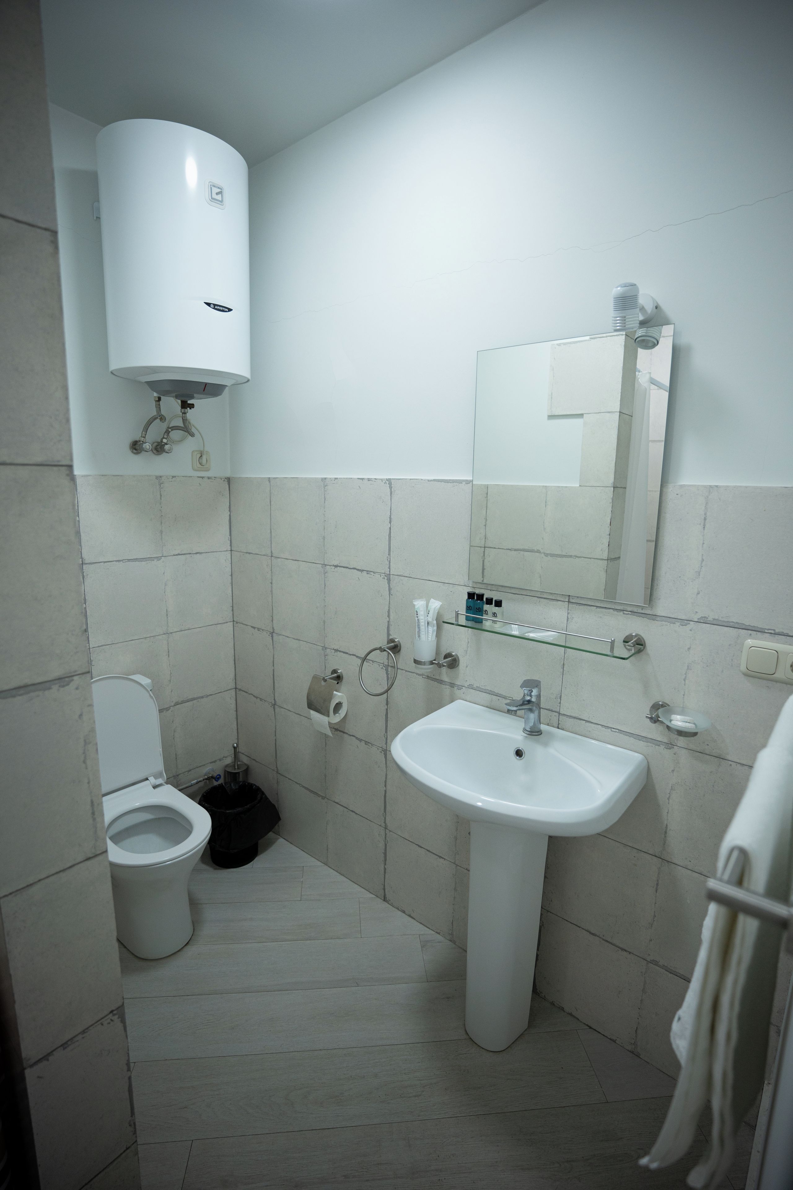 Un baño con inodoro, lavamanos, espejo y toallero.