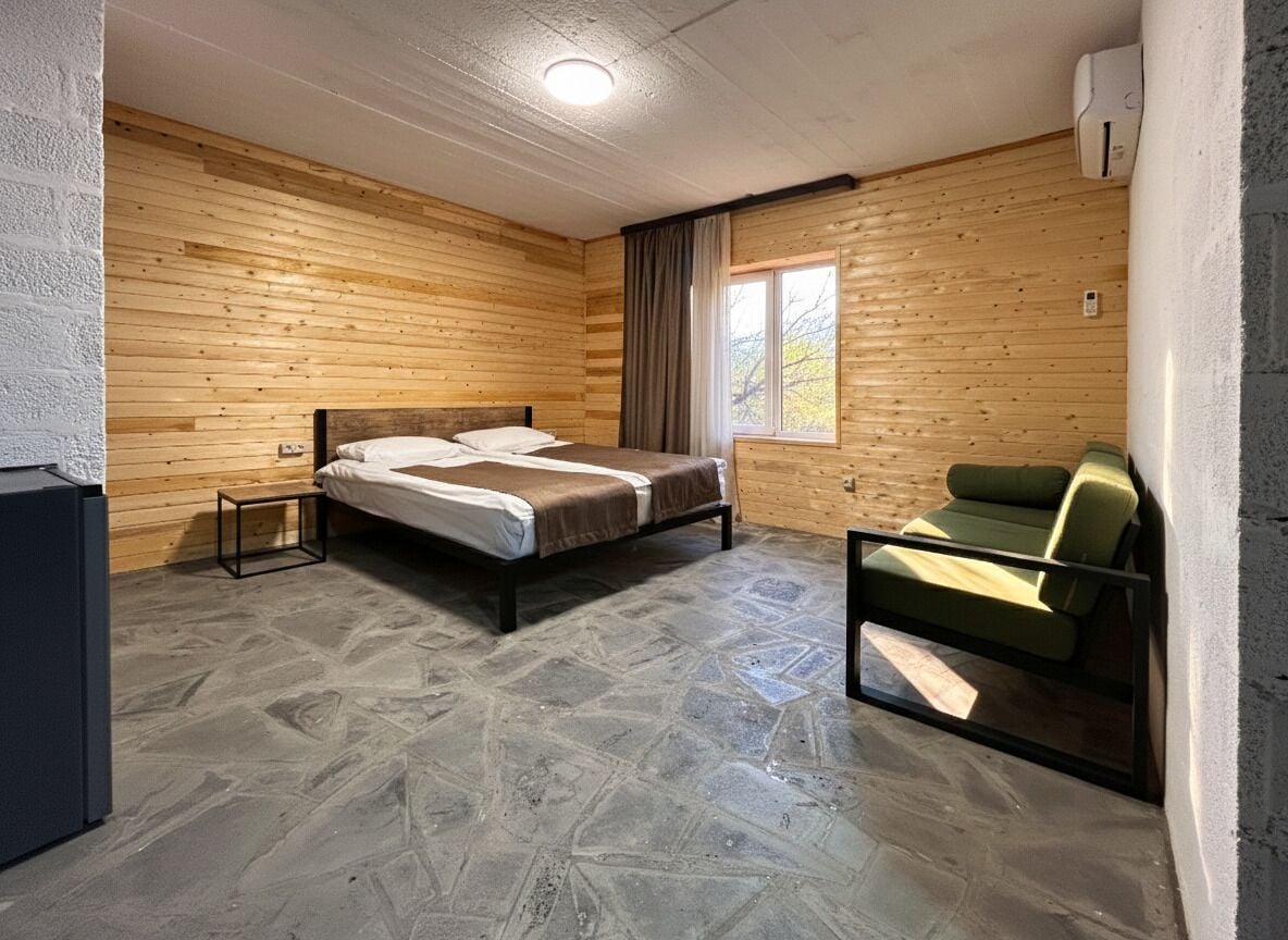 Una stanza con un letto, un tavolino, una poltrona e una finestra.