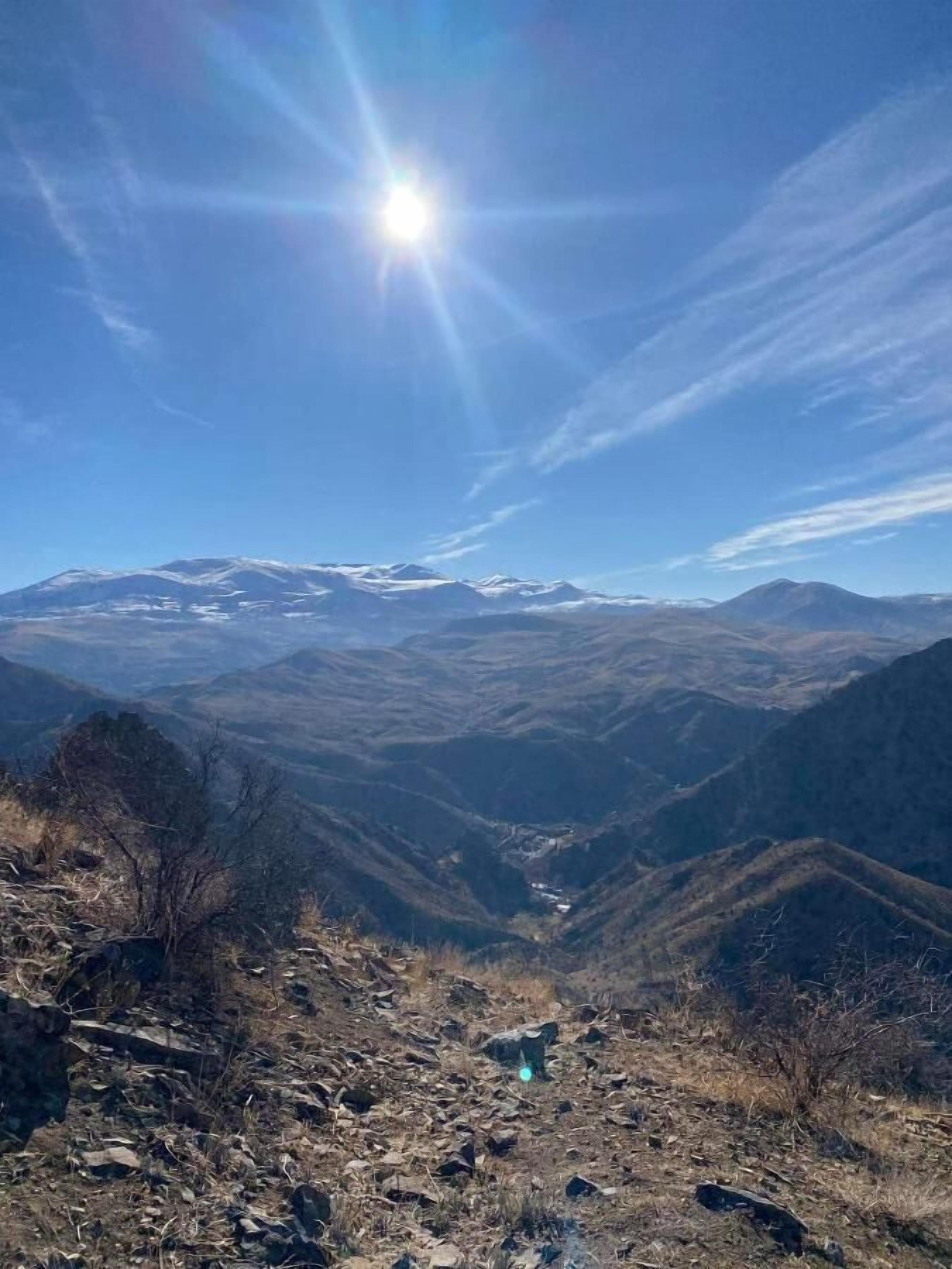 A mountainous landscape with a clear sky and sunlight.