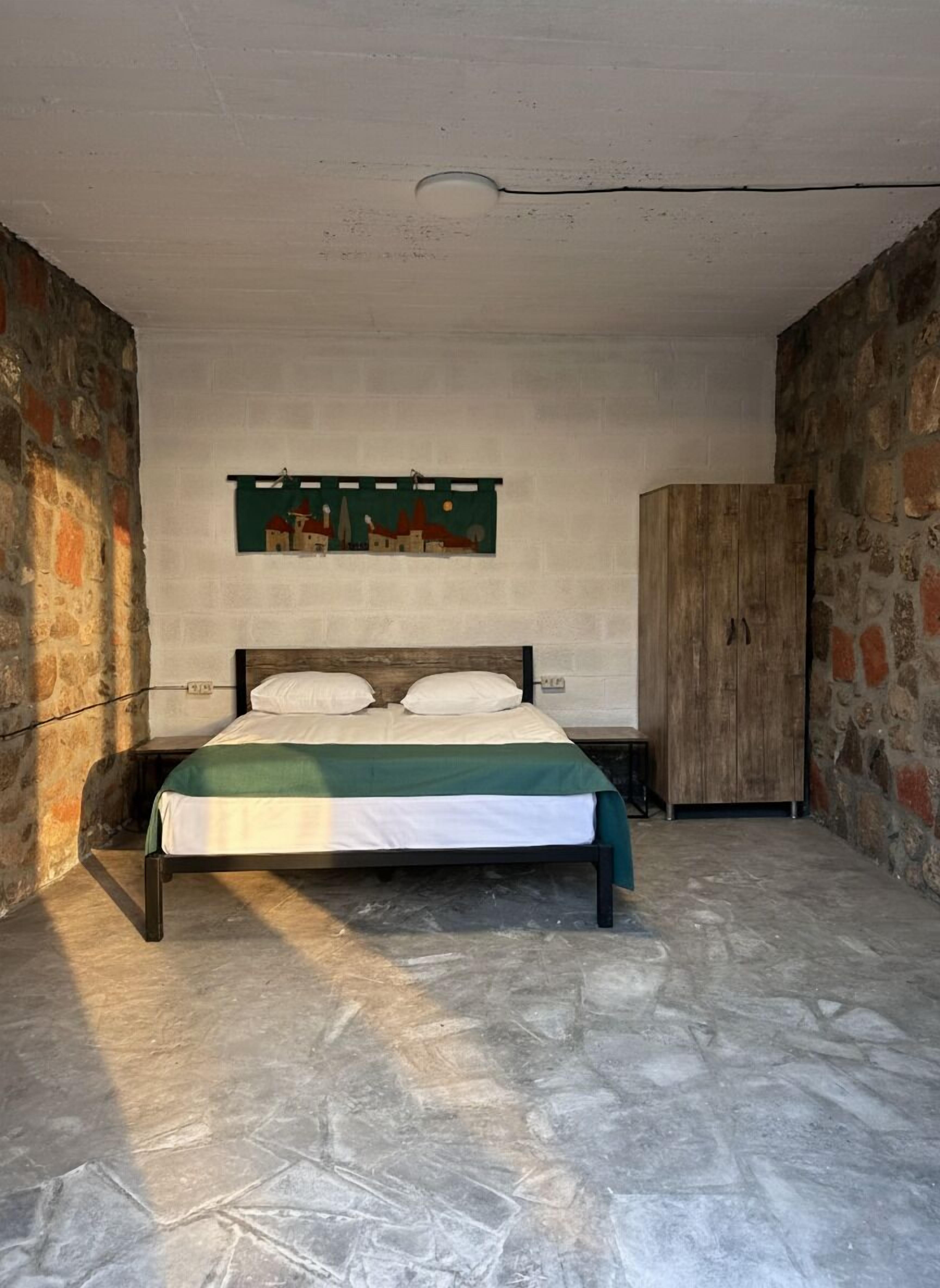 A bedroom with a bed, a wall-mounted artwork, and a wardrobe.