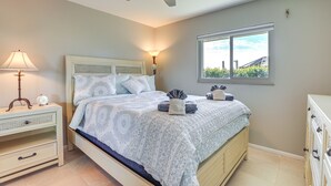 Un dormitorio con cama, mesitas de noche, ventilador de techo, ventana y cómoda.