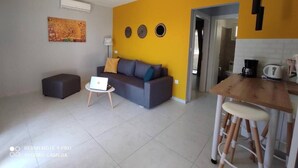 A modern living room with a sofa, a small table, and a dining area with stools. - Blue & Green Apts - Dassia, Corfu, 1 (Dassia)