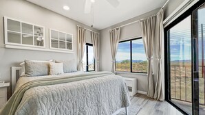 Ein Schlafzimmer mit einem großen Bett, einem Deckenventilator und einem Fenster mit Vorhängen.