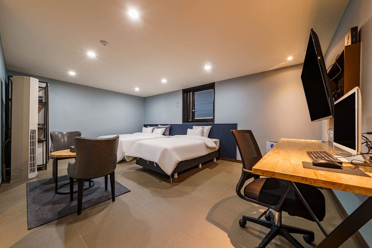 A modern hotel room with a bed, a desk, and a TV.